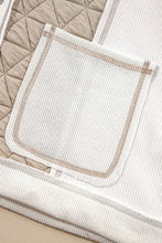 White quilted blanket with beige trim, pocket, and hooded bomber details