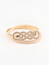 Gold tone bangle with interlocking knot buckle metal on textured band