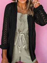 Weißer Spitzen- und Zopfmuster-Strickcardigan mit goldfarbenen Beschlägen über grünem Häkel-Overall mit Knopfleiste