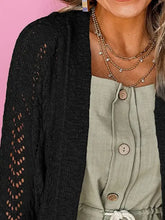 Schwarze Strickjacke mit Zopfmuster, weißen Spitzenärmeln und goldenen Knöpfen