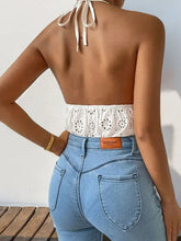 Back view of woman in white lace halter bodysuit and light blue jeans