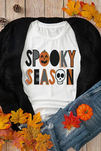 White spooky season graphic t-shirt with orange pumpkin and black skull designs