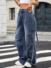 Wide leg cargo jeans in medium-wash blue denim with multiple pockets and adjustable side straps