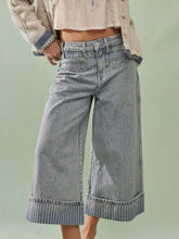 Light-wash denim wide-leg cropped jeans with rolled cuffs and a subtle striped pattern in culotte style