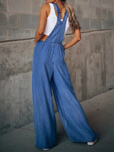 Woman in white crop top and wide leg denim overalls