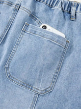 Light blue denim wide leg drawstring raw hem jeans with relaxed fit elastic waistband and front pocket holding a smartphone