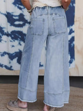 Wide leg drawstring raw hem light-wash denim jeans with frayed hems and relaxed high-rise elastic waist