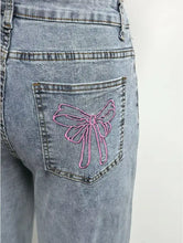 Back view of light-wash wide leg high waist jeans with pink embroidered bow on back pocket made of denim