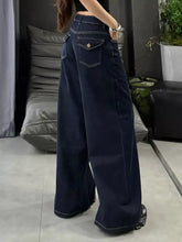 Dark blue wide leg jeans made of denim with contrasting white stitching and a single back pocket visible from the back side