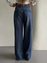 Wide leg vintage wash jeans in medium blue denim with classic back pockets and frayed hems shown from the back side
