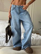 Light-wash denim wide leg jeans with a relaxed fit and visible stitching details featuring a wide-leg silhouette