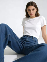 White cotton t-shirt with crew neckline and short sleeves paired with wide leg washed jeans