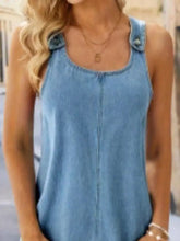 Wide strap denim overall dress with pockets paired with a light blue denim sleeveless top with buttoned shoulder straps