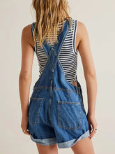 Woman in wide strap square neck denim overalls over striped tank top