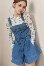 Woman in wide strap square neck denim overalls with floral top