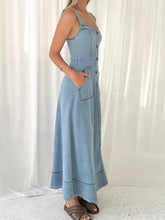A light blue denim dress with wide strap sweetheart neck thin straps and a button-down front design