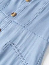 Light blue denim dress with wide strap sweetheart neck, tan wooden buttons, and stitched pocket details