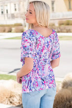 Women’s colorful floral print V-neck blouse with ruffled hem and light blue jeans