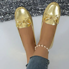 Pair of gold metallic womens round toe flats with decorative bows