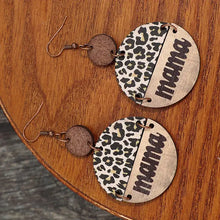 Runda örhängen i trä med leopardmönster och texten "mama"