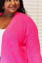 Neon pink drop shoulder cardigan sweater with gold chain and hoop earrings