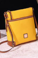 Bright yellow leather crossbody bag with brown trim and front zipper pocket