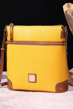 Yellow leather crossbody bag with brown trim and zipper pocket