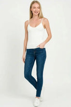 A pair of dark wash skinny jeans with five-pocket design and subtle fading styled with a zenana double layered v neck spaghetti cami