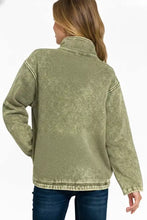 Olive green distressed denim jacket with high collar and ribbed cuffs complementing high neck kangaroo pocket style