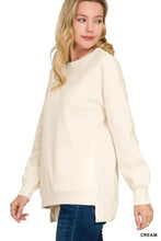 Cream-colored fleece sweatshirt with long sleeves, relaxed fit, asymmetrical hemline, and pockets in plus size by zenana