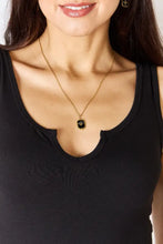 Gold-toned necklace with black rectangular pendant embossed with gold emblem worn with zenana microfiber notched sleeveless bodysuit