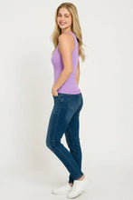 A woman wears a lavender Zenana racer back rib tank top made of ribbed knit fabric paired with dark jeans and white sneakers