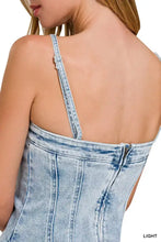 Light-wash denim corset top with exposed seam, thin distressed spaghetti straps, and back zipper closure