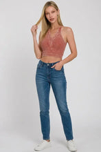 A woman wears a dusty rose washed ribbed seamless button v-neck tank top with textured fabric and halter neckline